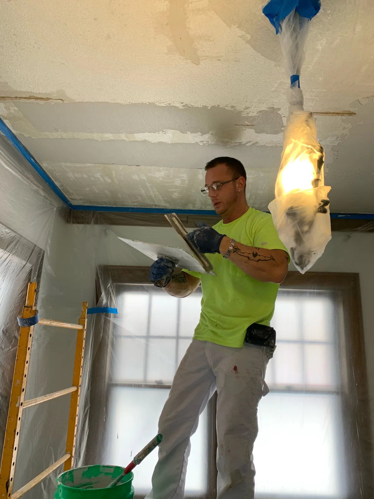 Our third-generation plasterer with hawk and trowel, plastering a ceiling by hand